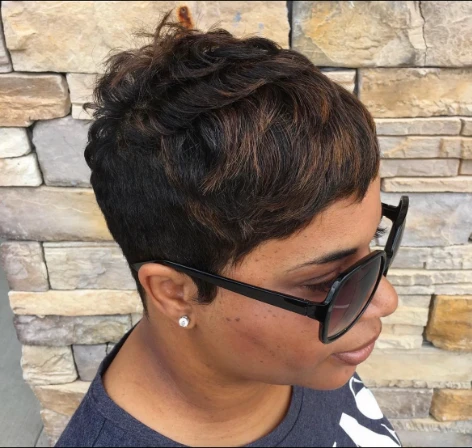 Profile of a textured short pixie with warm highlights against a stone wall